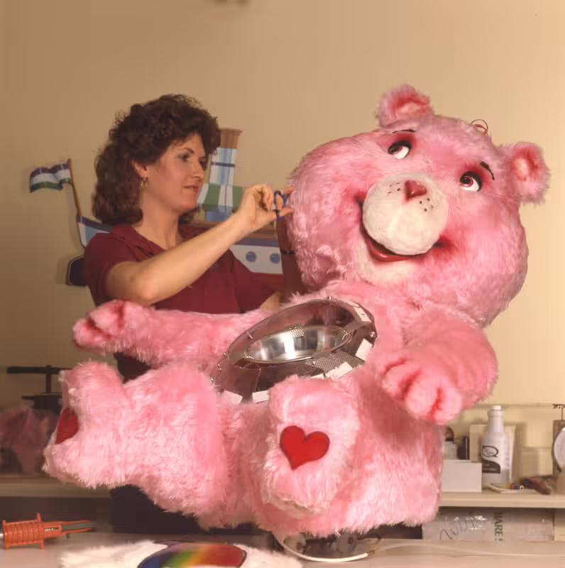 Donna Gentry costuming the Dunia Cheer Bear figure at Sally (1986)